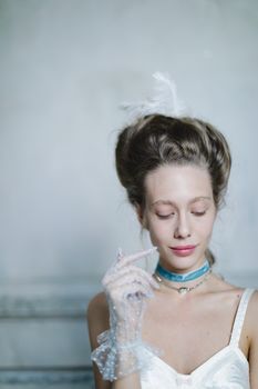 A sophisticated woman in lace gloves and a stylish choker exhibiting a serene expression indoors.