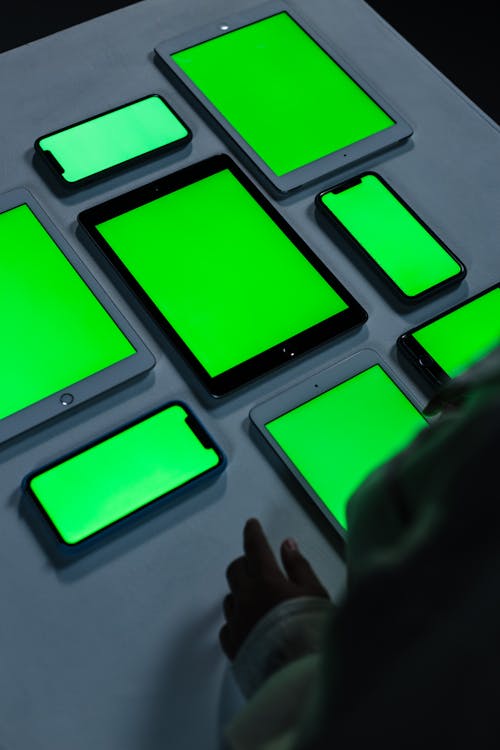 Table with smart phones and tablets with green screen