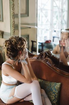 Young woman in elegant lingerie gazing at her reflection in a stylish indoor setting.