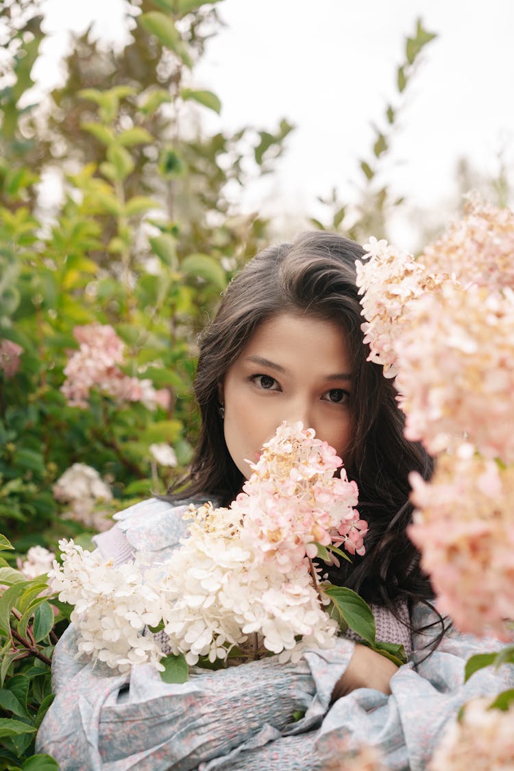 Woman In The Garden Covering Her Mouth With Flowers