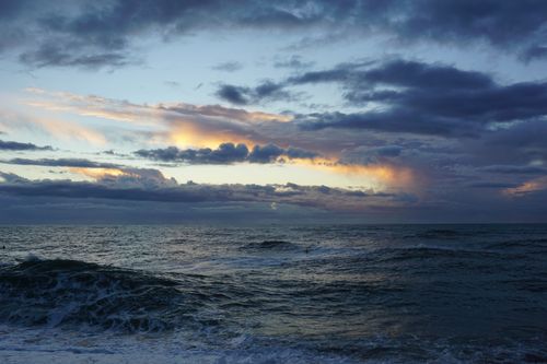Free A striking ocean view captured at sunset, highlighting dramatic clouds and waves. Stock Photo