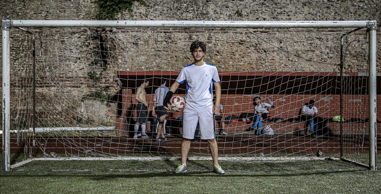 Free Man in White Soccer Uniform Standing by  the Goal Net Stock Photo