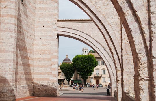 View through stone arches in a European city with people strolling beneath.