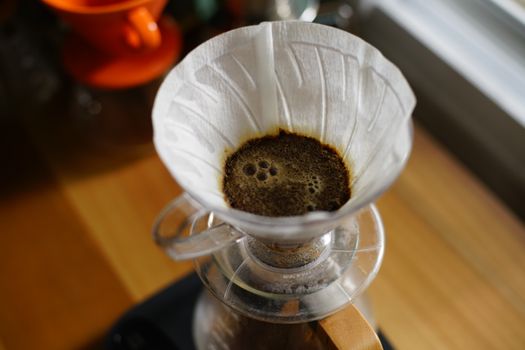 Freshly brewed coffee dripping through a paper filter in a glass pourover carafe, capturing rich aromas.