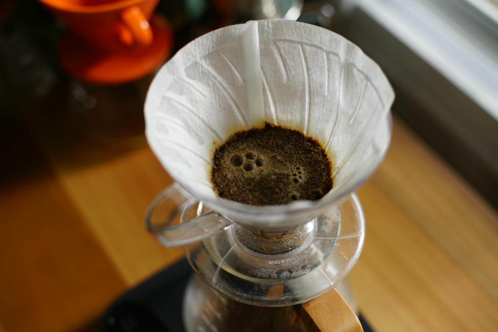 Pour-over coffee dripping through a white paper filter into glass carafe