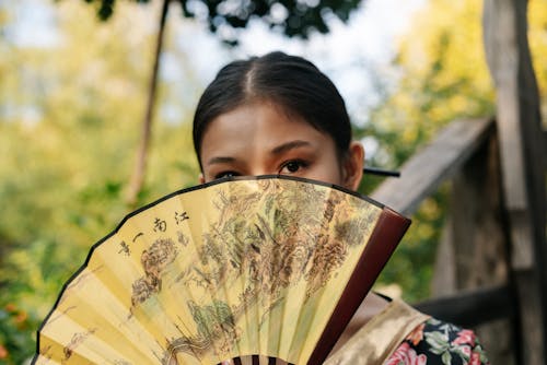 Close-Up Shot of a Woman Holding a Hand Fan