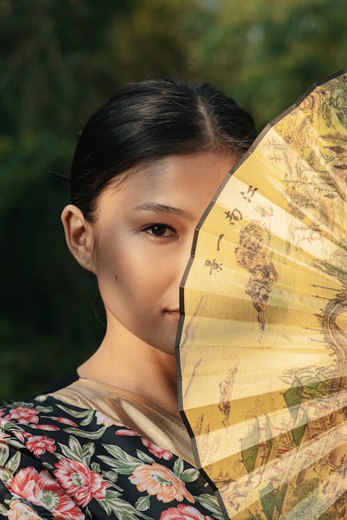 Free Woman Covering Her Face with Hand Fan Stock Photo