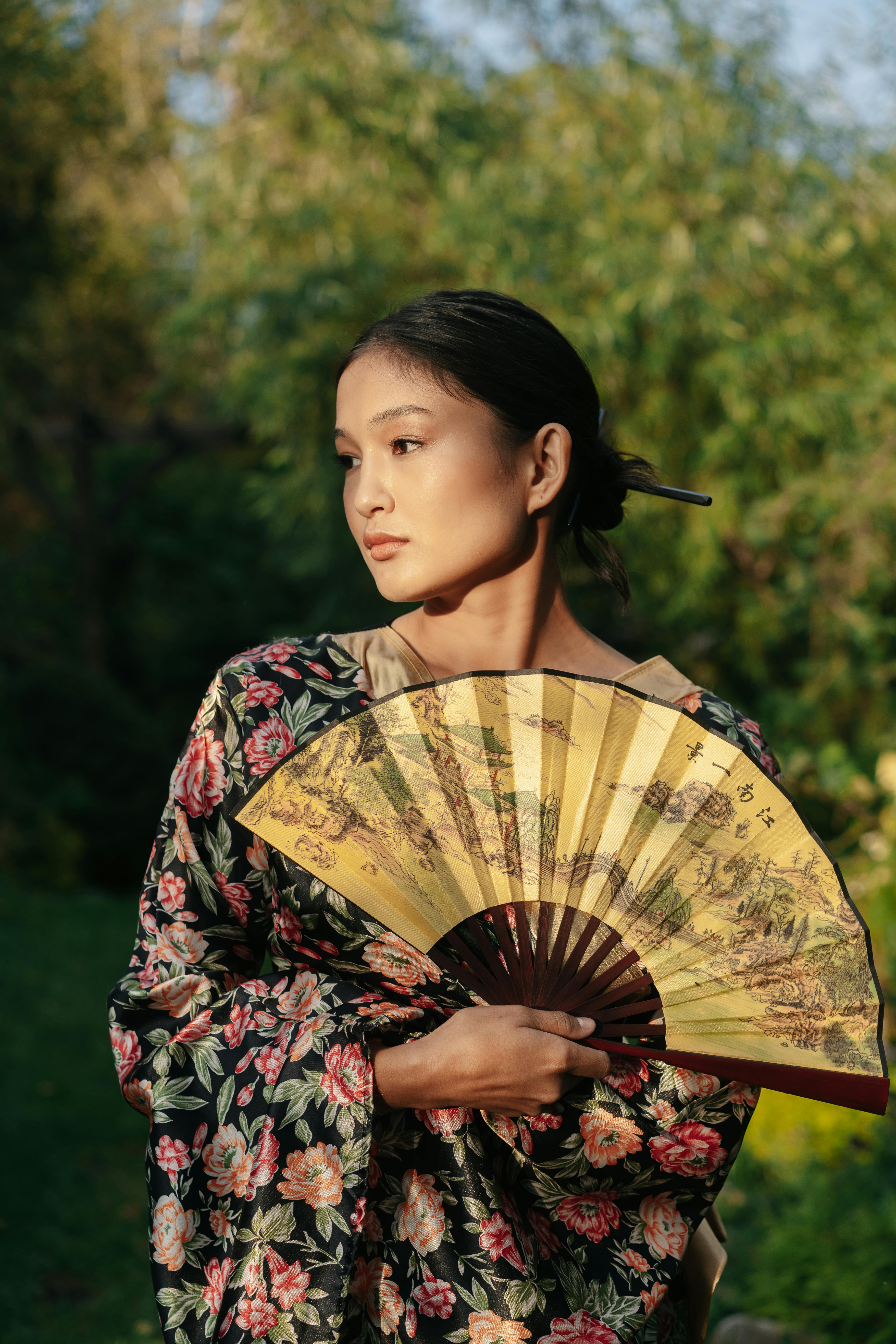 身着花和服的年轻女子手持扇子，在宁静的花园中展示日本传统文化