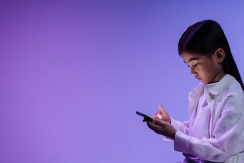 Girl in White Long Sleeve Shirt Holding Black Mobile Phone