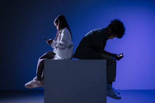 Free Silhouettes of kids using smartphones on a block, set against blue studio lighting. Stock Photo