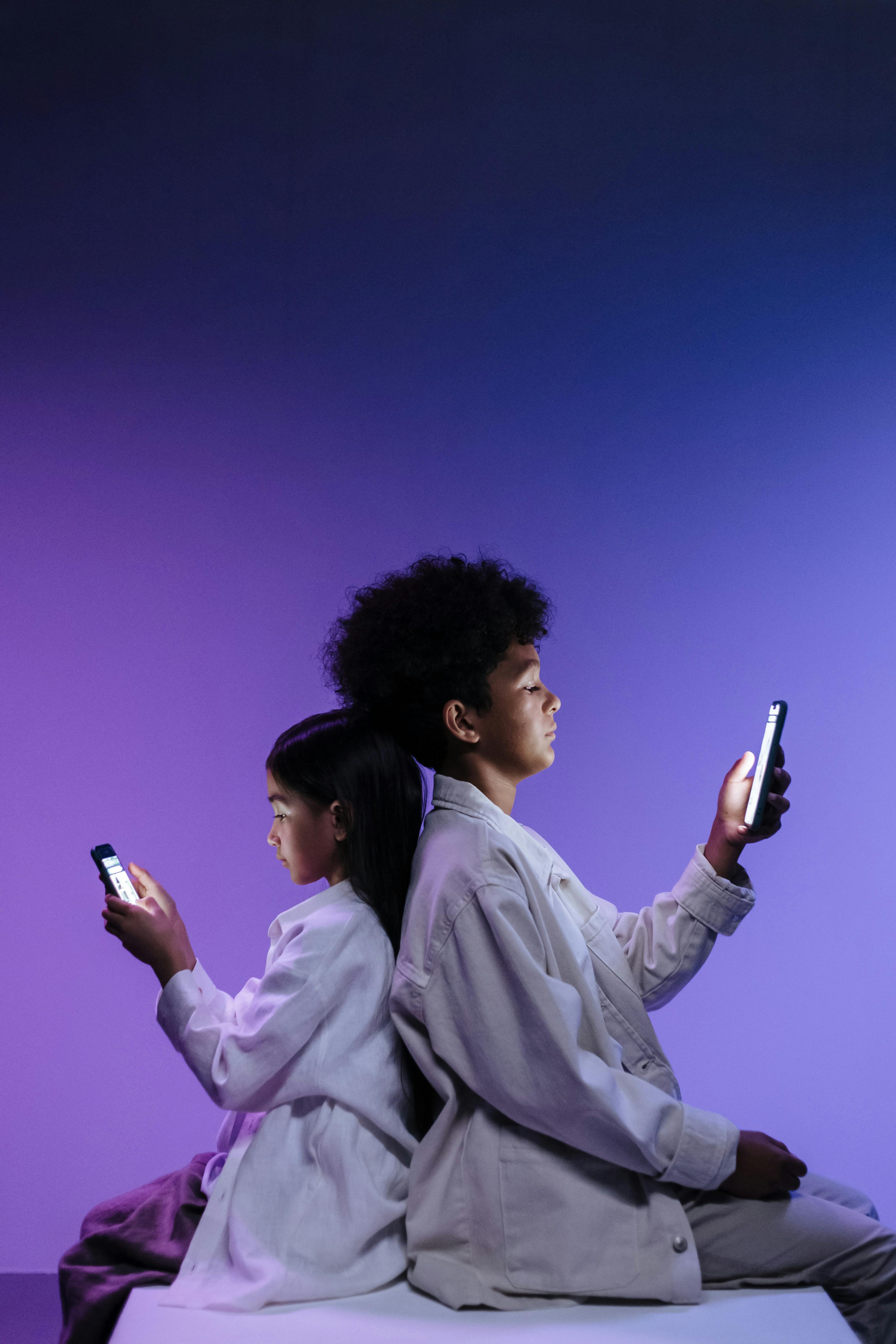 Boy and a Girl Sitting Back to Back Using Cellphone · Free Stock Photo