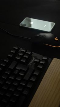 Minimalist tech setup showcasing a keyboard, mouse, and smartphone in a dark environment.