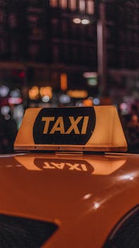 Yellow taxi with 'TAXI' sign at night, reflecting city lights and bokeh effect.