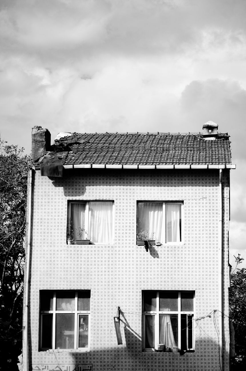 A dramatic black and white photograph showcasing a vintage house exterior with windows.