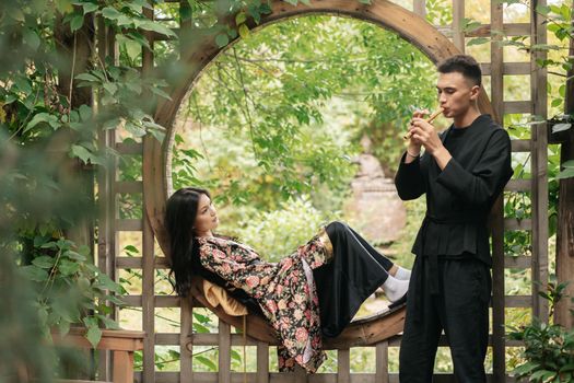 A Man in Black Kimono Playing the  Flute for a Woman