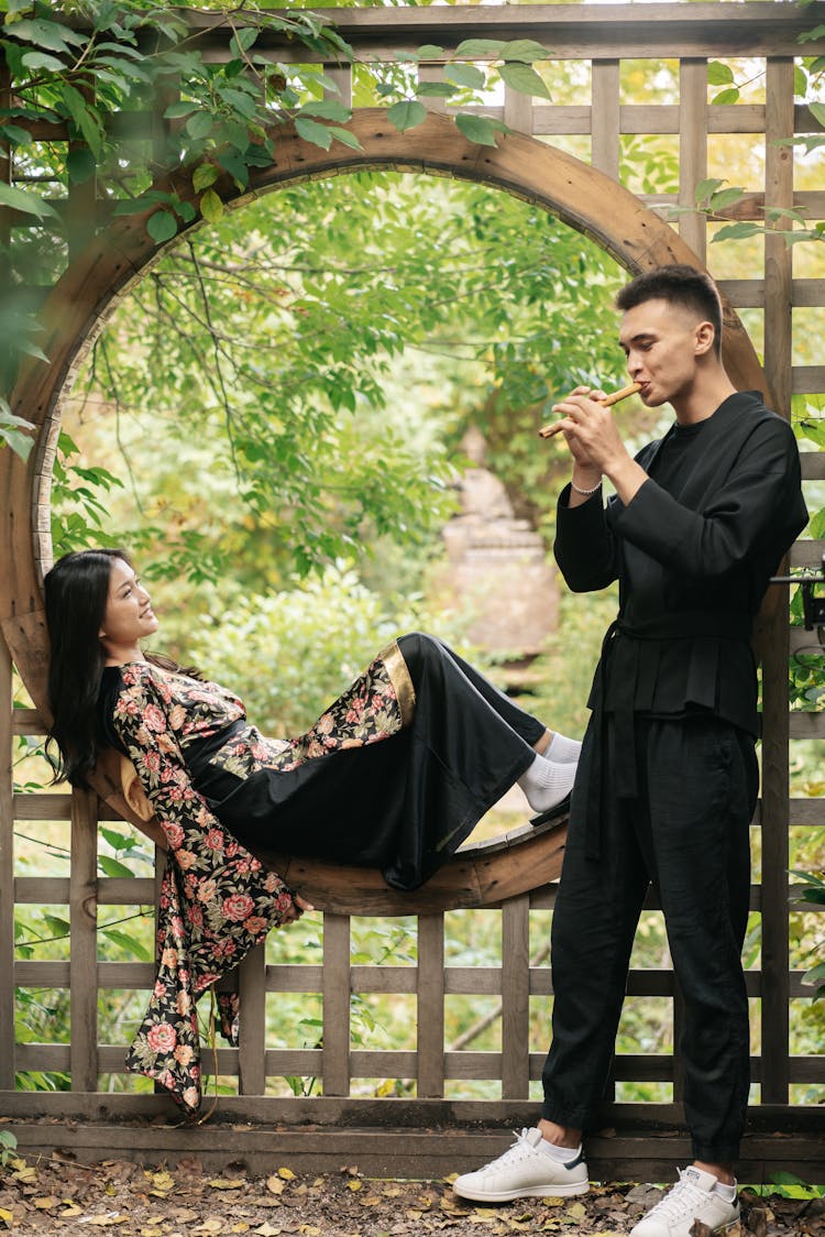 A Man Playing The Flute For A Woman In The Garden