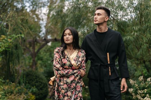 Young couple in traditional floral attire walking peacefully in a garden.