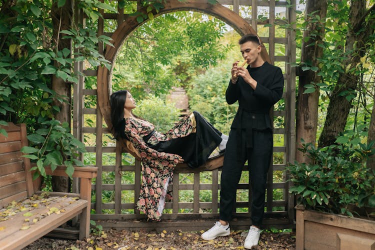 A Man Playing The Flute For A Woman In A Garden