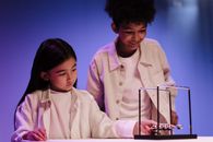 Boy and girl moving ball of newton s cradle