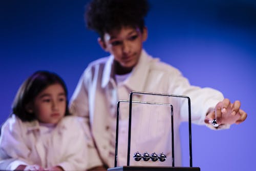 Boy and girl making move a ball of newton s cradle