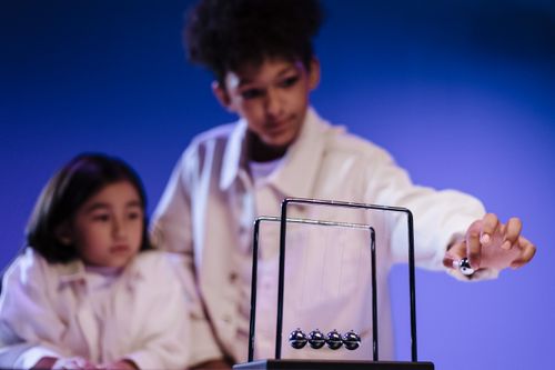 Free Engaged children learning physics through hands-on play with Newton's Cradle. Stock Photo