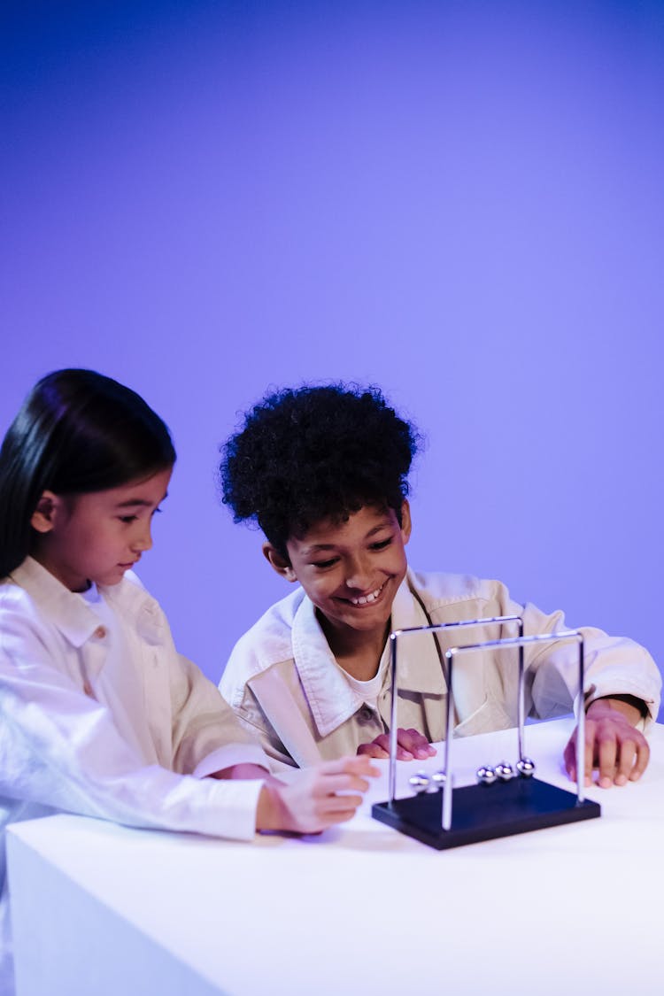 Boy And Girl Are Playing With Newton S Cradle