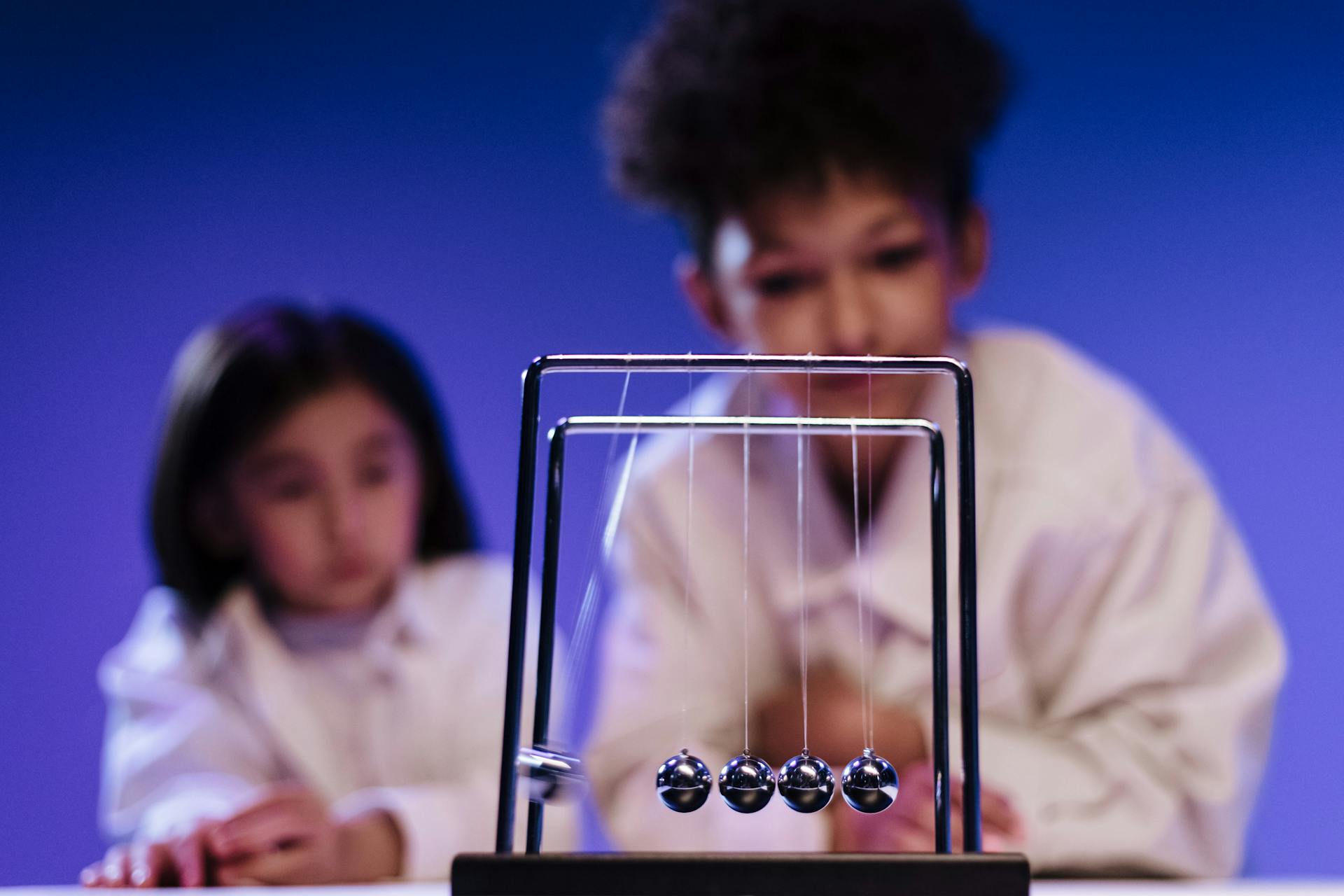 Boy and girl observing balls of newton s cradle moving