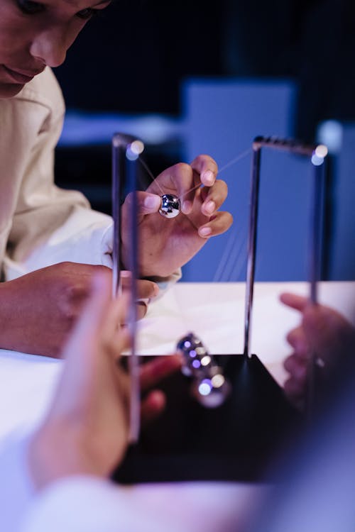 Boy moving a ball of newton s cradle