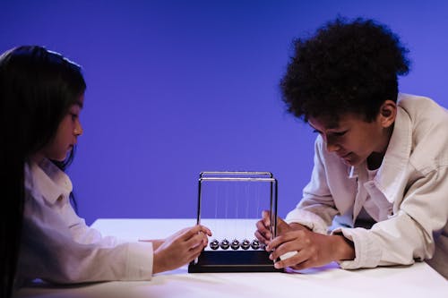 Boy and girl holding the newton s cradle