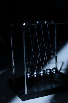 Newton's cradle in a dark setting, illustrating physics concepts with elegant design.