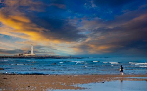 Free A breathtaking view of a lighthouse on the coast with dramatic skies at sunset. Stock Photo