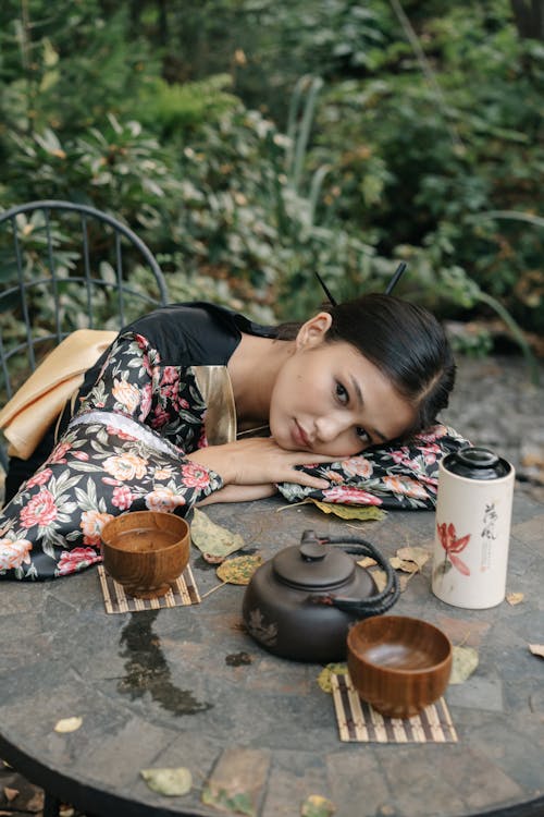Young Woman in a Floral Kimono Lying on a Table with a Teapot and a Tea Bowls