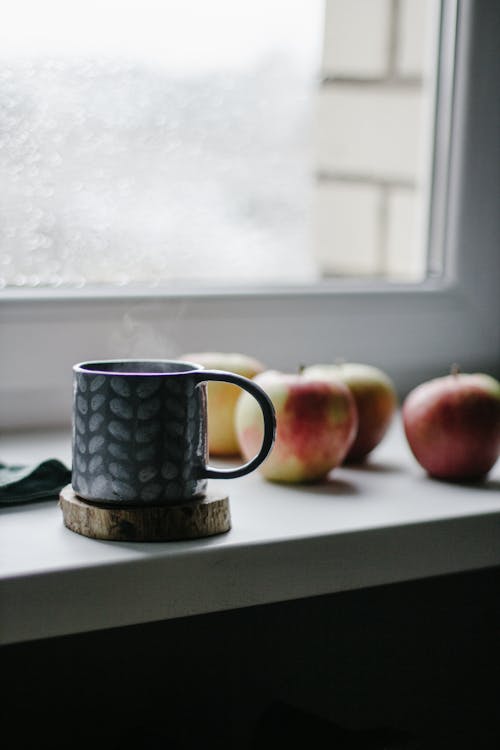 A Mug and Apples by a Window