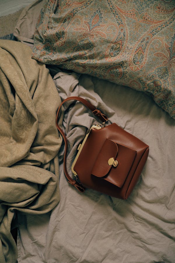 Small brown leather bag on bed