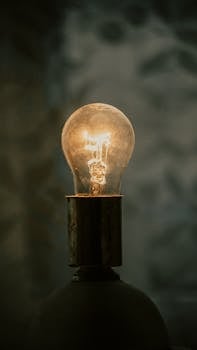 A close-up of a glowing light bulb with a warm ambiance against a blurred background.