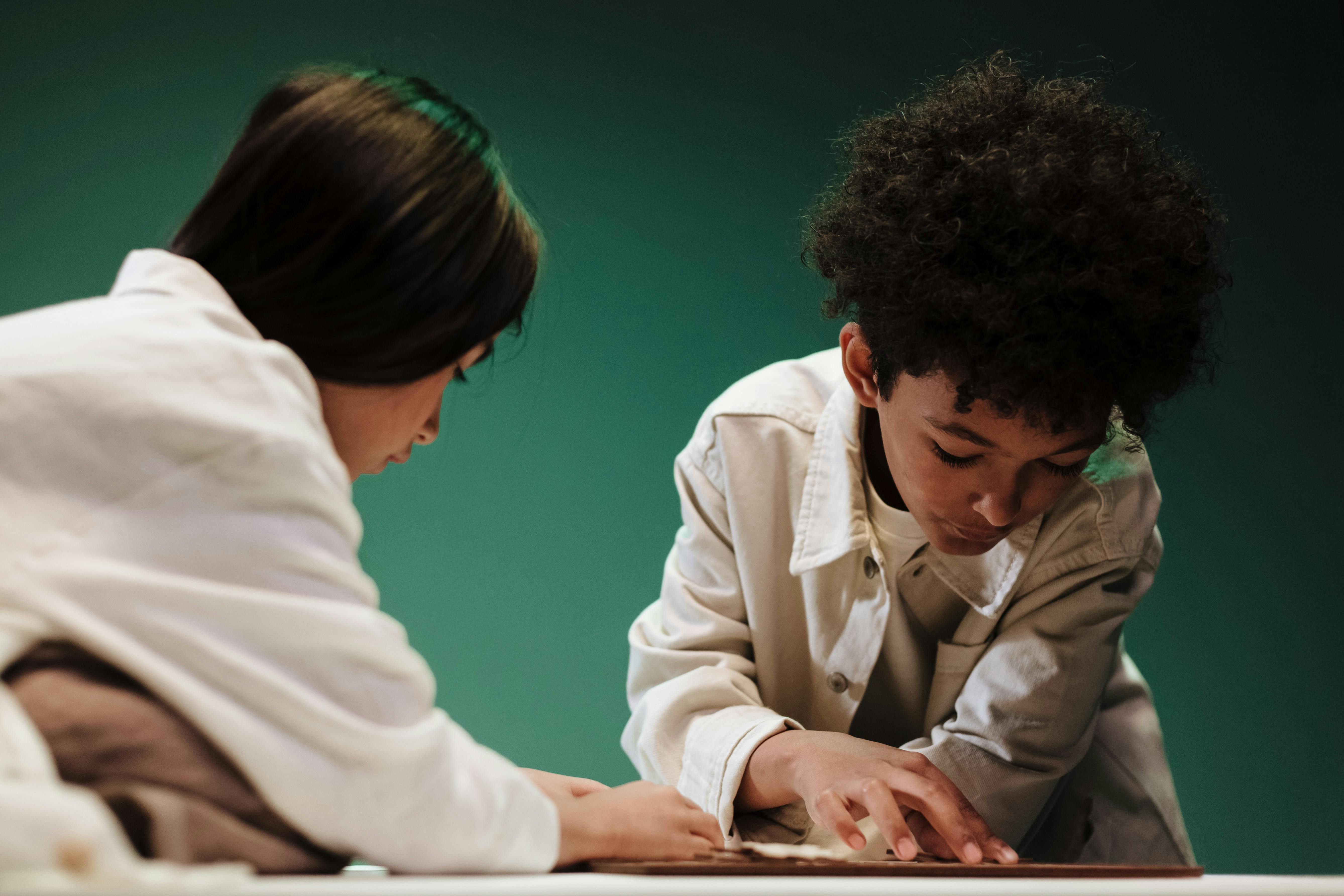 teenage boy and girl adjusting piece of jigsaw puzzle