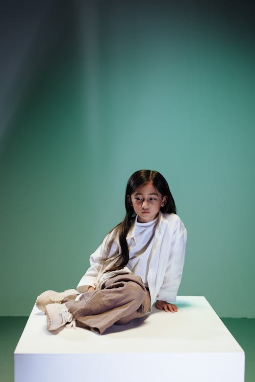 Teenage girl sitting on white podium