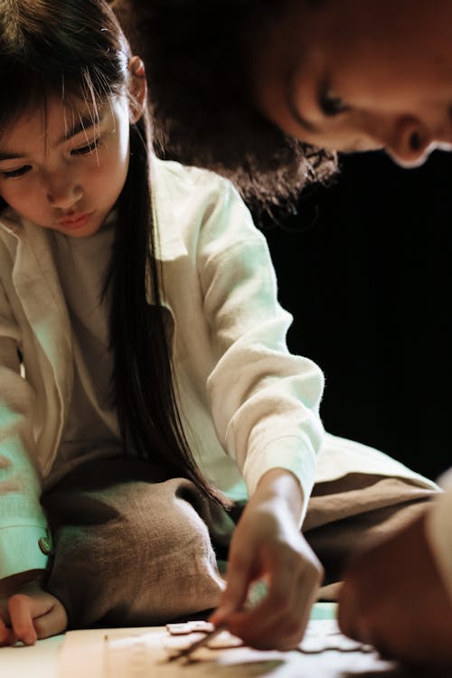 Free Teenage girl kneeling on table and doing puzzles with her big brother Stock Photo