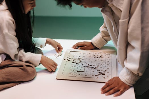 Two kids collaborating on a jigsaw puzzle on a table indoors.