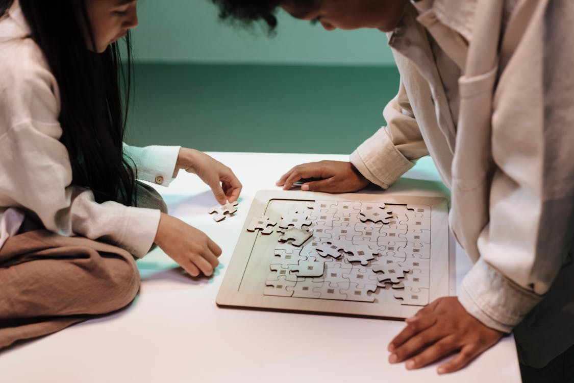 Free Teenage girl sitting on table and doing jigsaw puzzles with her brother Stock Photo