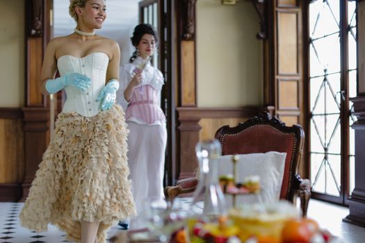 Elegant palace scene with women in vintage costumes enjoying a refined indoor setting.