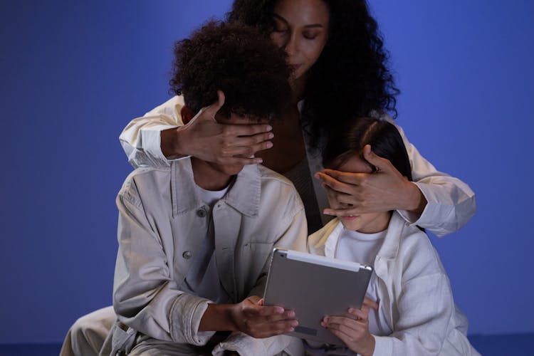 Mother Covering The Kids Eyes While They Are Holding The Tablet 