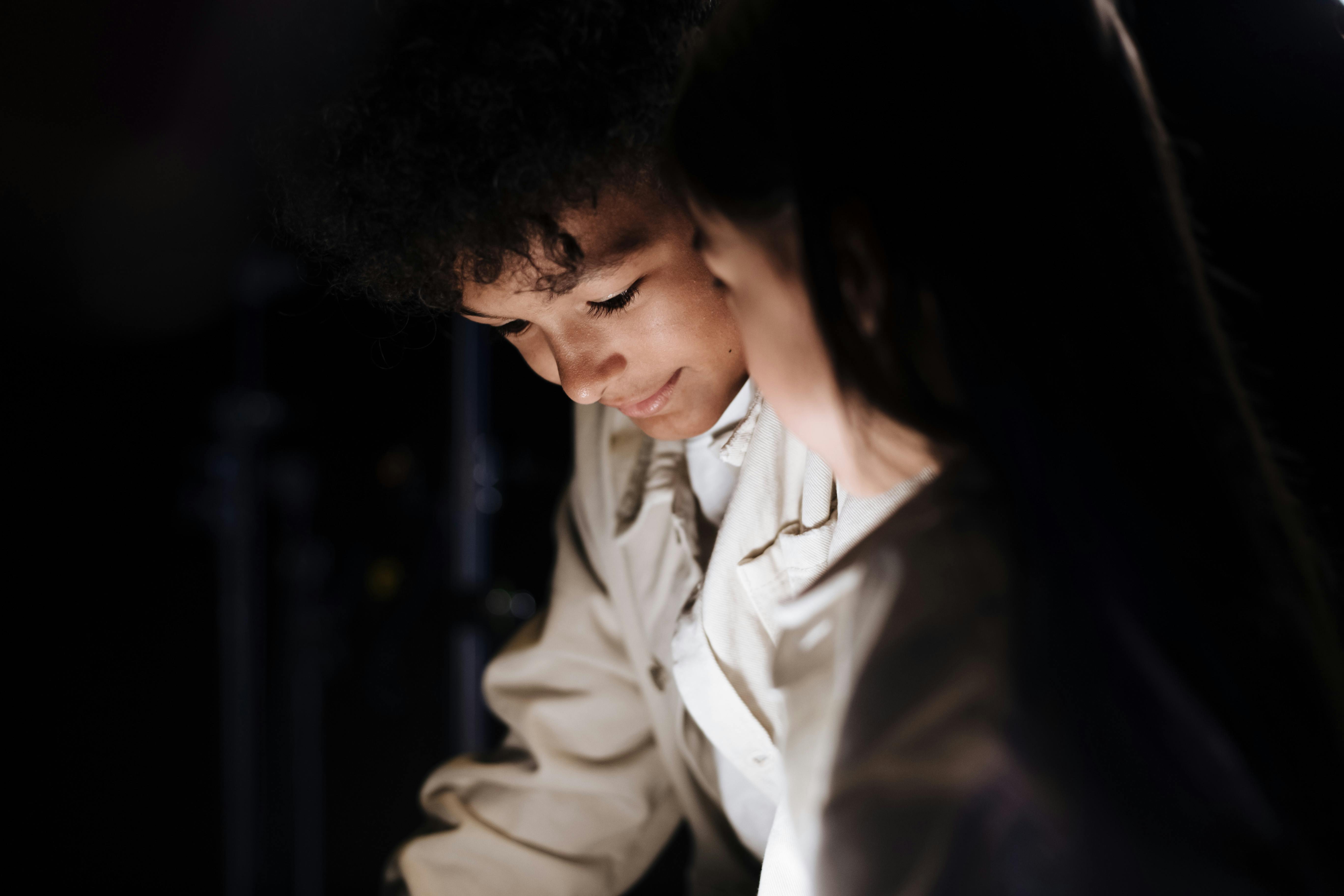 Young boy leaning over glowing screen and smiling