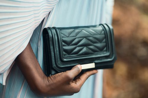 Free Close-up of a stylish black purse held by a person outdoors, showcasing elegance and fashion. Stock Photo