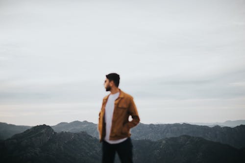 Free Man in Brown Jacket Standing on Top of Mountain Stock Photo