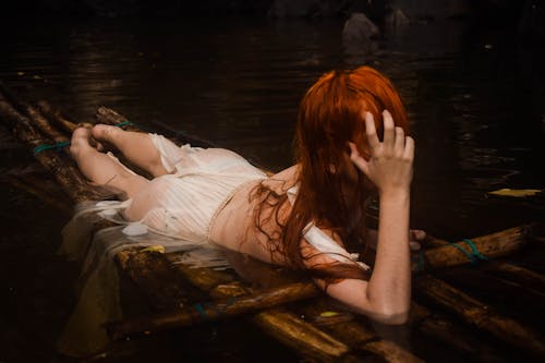 Free Woman Lying on Wooden Raft Covering Her Face Stock Photo
