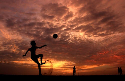 無料 日没時にボールを遊ぶ少年のシルエット 写真素材