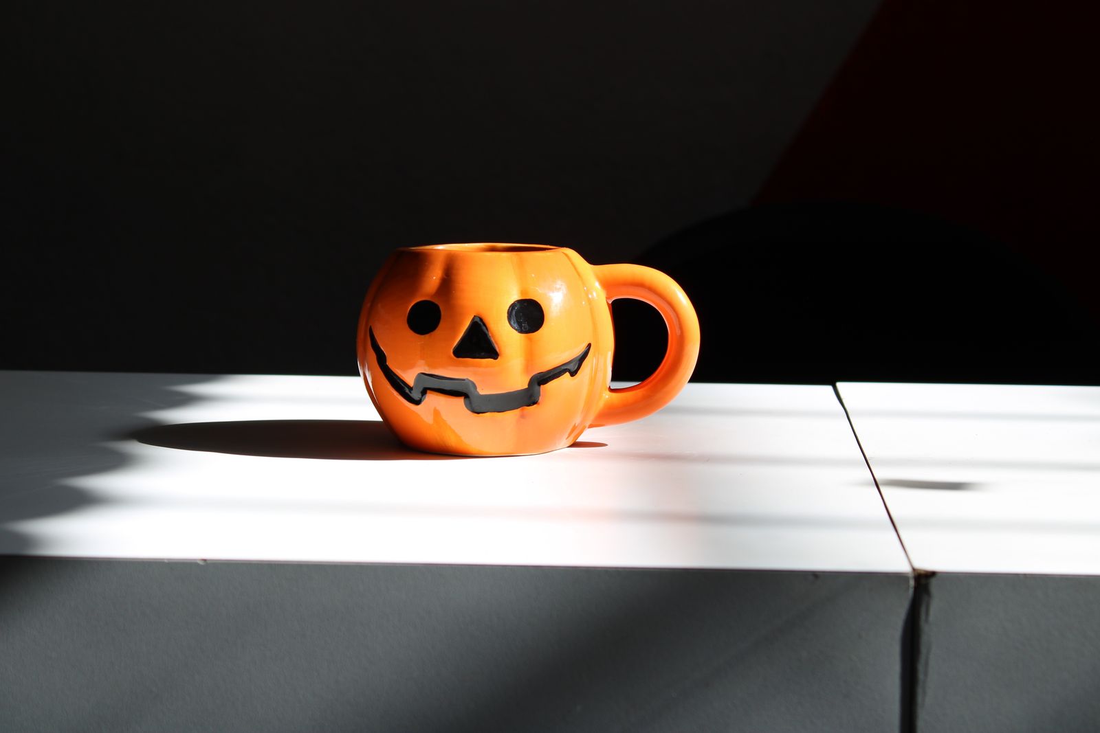An orange pumpkin-shaped mug on a pale surface