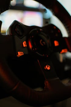 A detailed close-up of a gaming steering wheel, highlighted by console buttons.