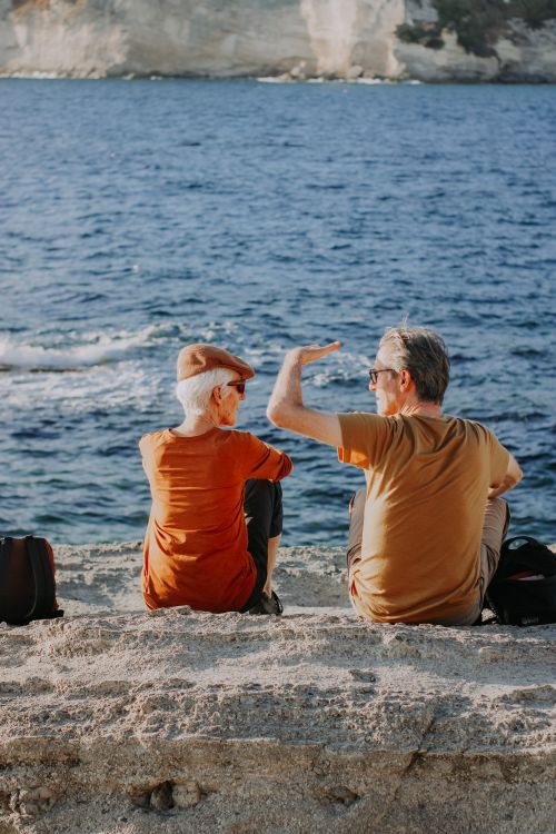 Free Senior couple sitting by the ocean, enjoying the serene waves and beautiful scenery. Stock Photo